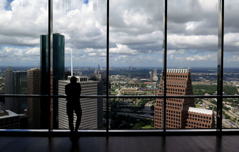Silhouette man looking towards buildings through window in city