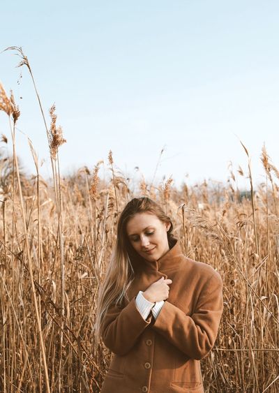 Woman in camel coat at pampas grass field