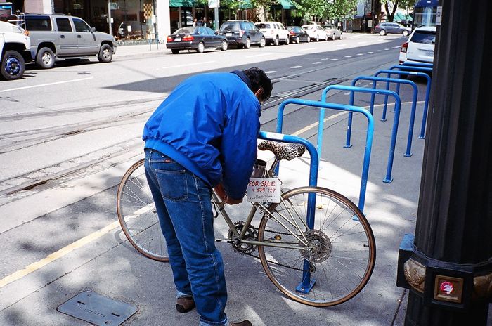 Man locking bicycle on rack at sidewalk