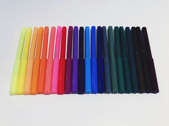 High angle view of multi colored pencils on table against white background