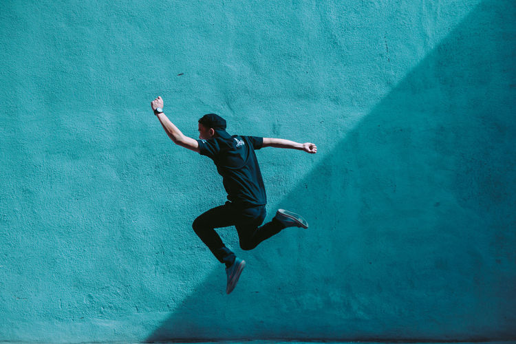 Man jumping against blue wall
