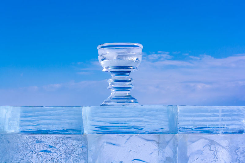 Close-up of glass of water against blue sky