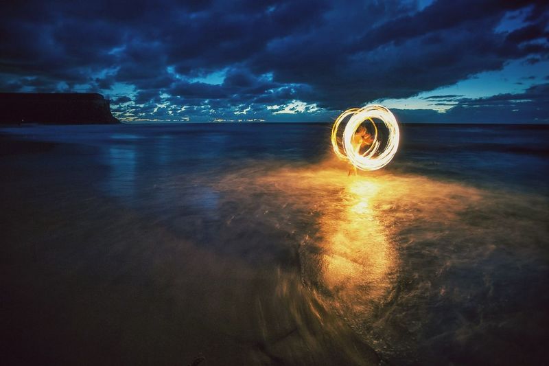 Person with illuminated wire wool on shore