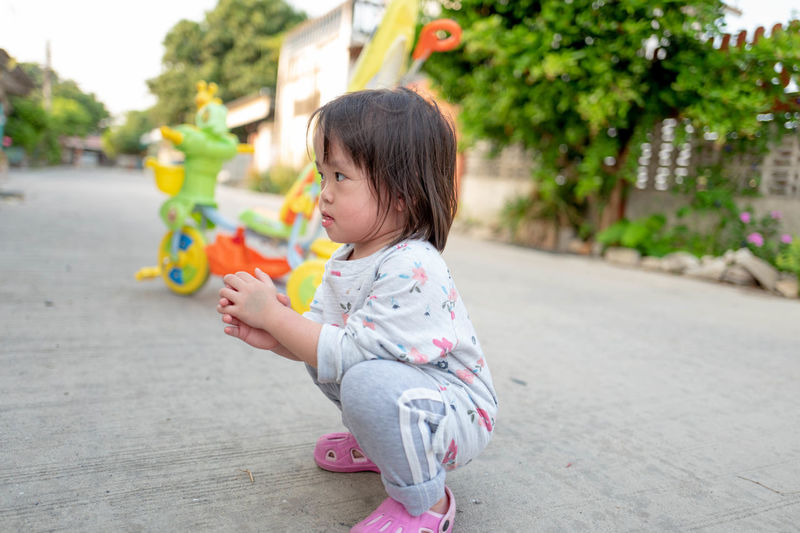 Cute girl crouching on footpath