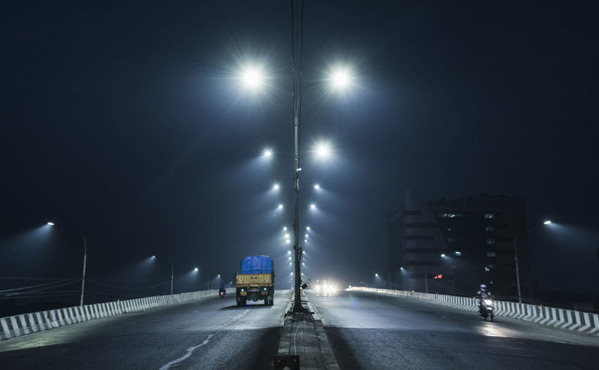 Cars on illuminated road in city at night