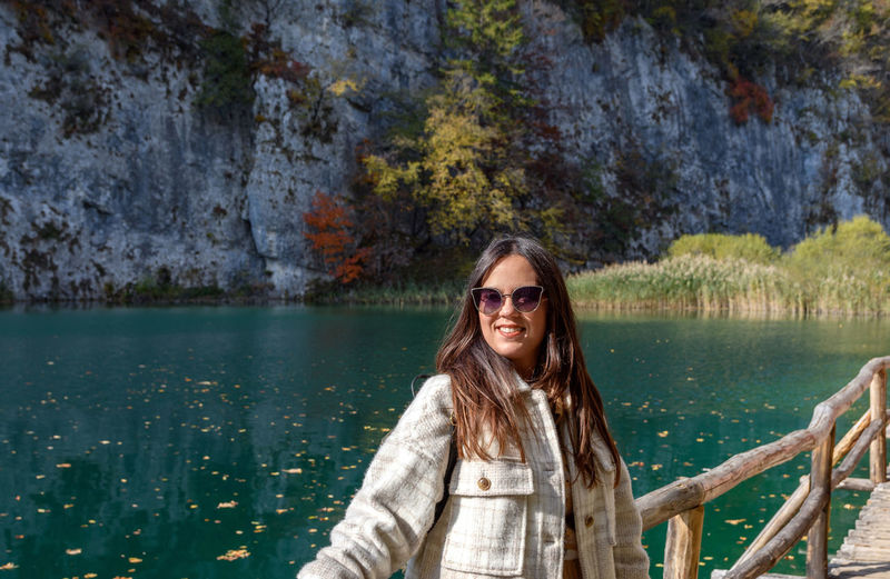 Beautiful young woman on wooden path on shore of beautiful lake in plitvice lakes national park
