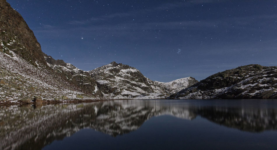 Scenic view of lake and mountains against sky at night