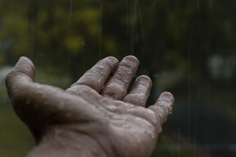 Close-up of human hand during rainy season