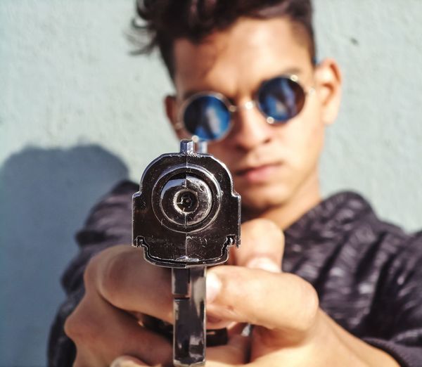 Portrait of man holding fake gun against the wall.
