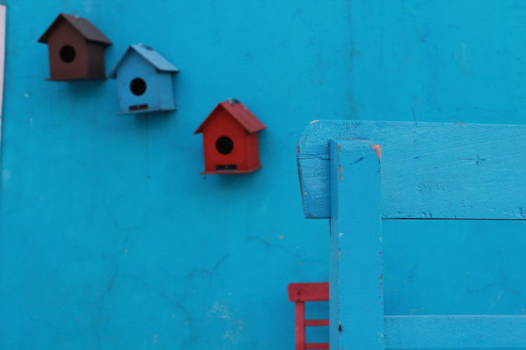 Close-up of birdhouse against blue wall