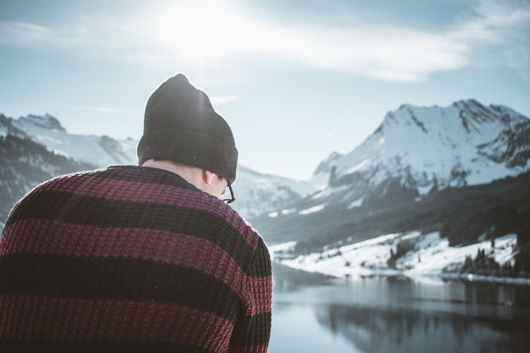 Man looking at lake against snowcapped mountain