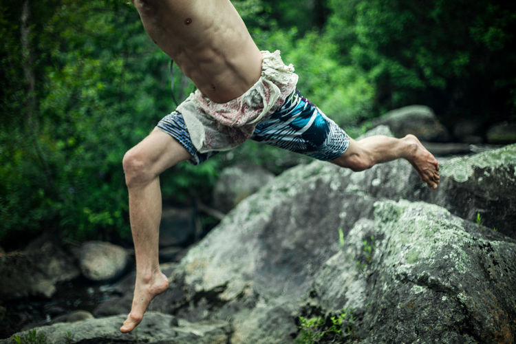 Low section of man jumping over rock