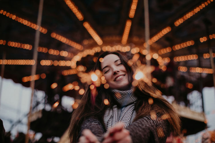 Young happy woman with sparklers on a background of golden bokeh holiday lights. outdoor portrait 