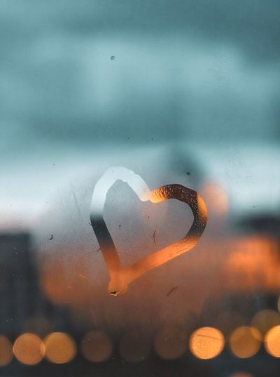 Close-up of heart shape seen through wet glass window