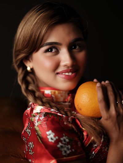 Portrait of young woman holding oranges