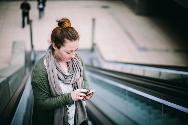 Young woman using mobile phone at railroad station