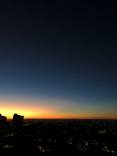 Illuminated buildings in city against sky at sunset