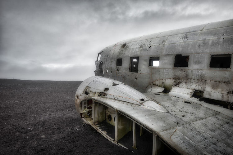 Abandoned airplane on beach against sky
