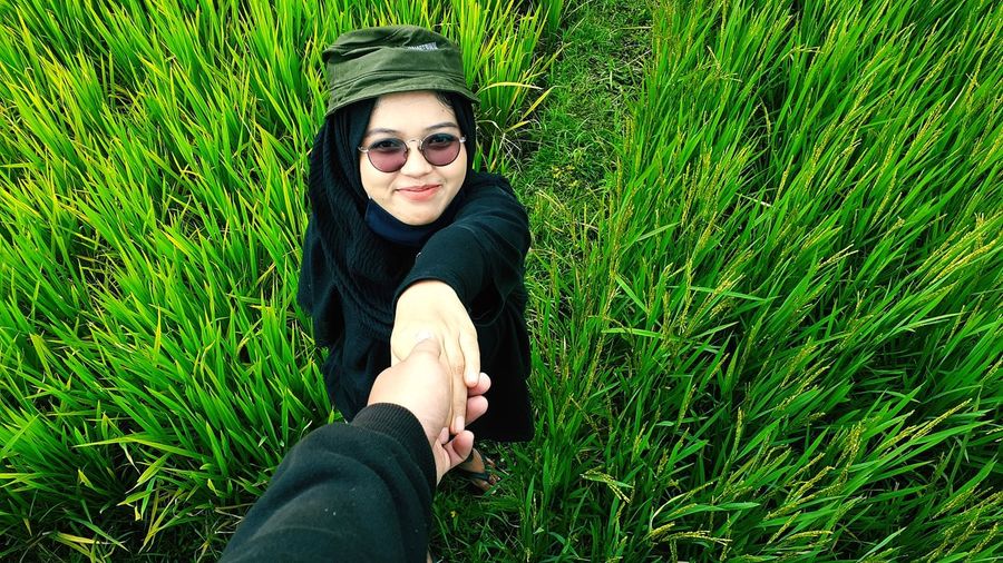 Young woman wearing sunglasses while holding boyfriend hand