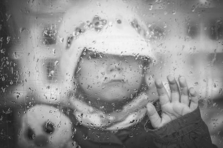 Child seen through wet window in rainy season
