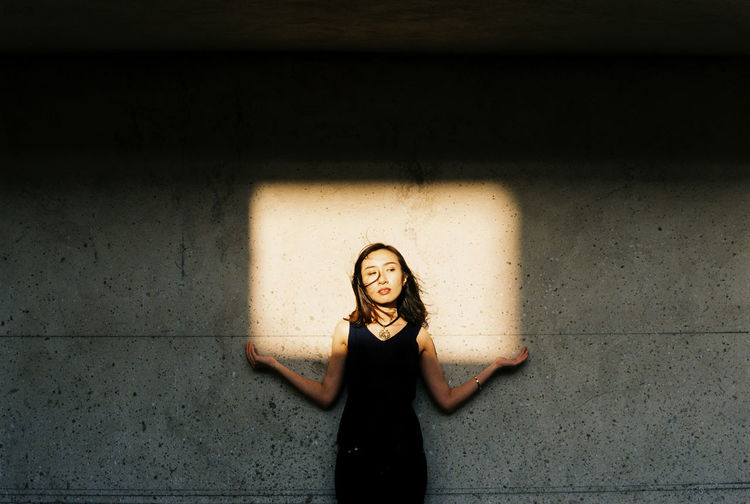 Optical illusion of young woman holding window shadow falling on wall