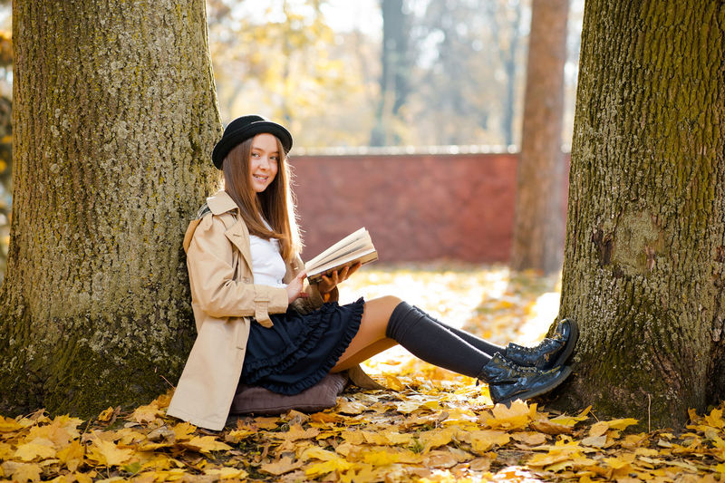 Teenager girl reading book while sitting amidst tree