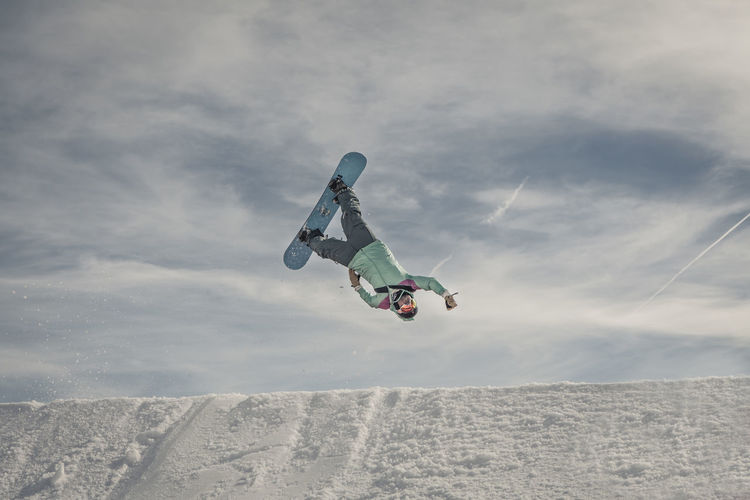 Snowboarder jumping against sky at mountain