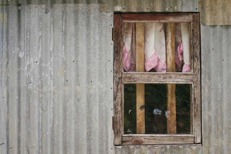 Close-up of pink window on wooden wall