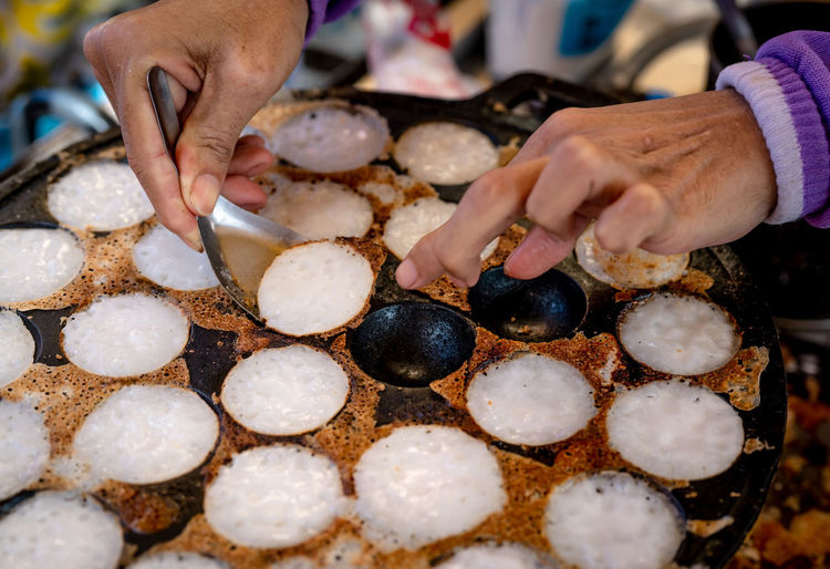 Mortar-toasted pastry or kanom krok is thai traditional dessert. woman hand removing kanom krok.