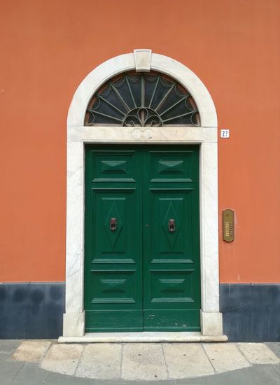 Italian green old-fashioned door on orange wall