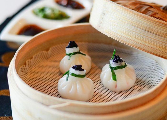 Close-up of chinese dumplings with caviar in bamboo steamer on table