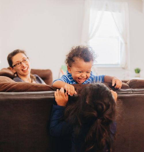 Smiling mother with kids sitting on sofa at home