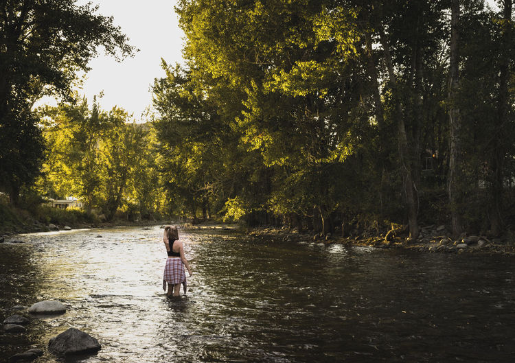 Woman standing in lake against trees