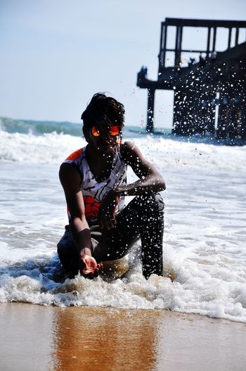 Full length of man sitting at sea shore