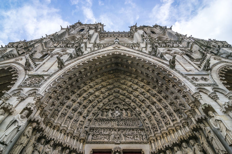 Low angle view of cathedral building in amiens against cloudy sky