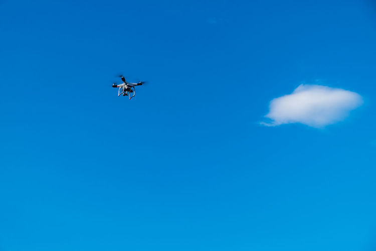 Low angle view of drone flying in blue sky
