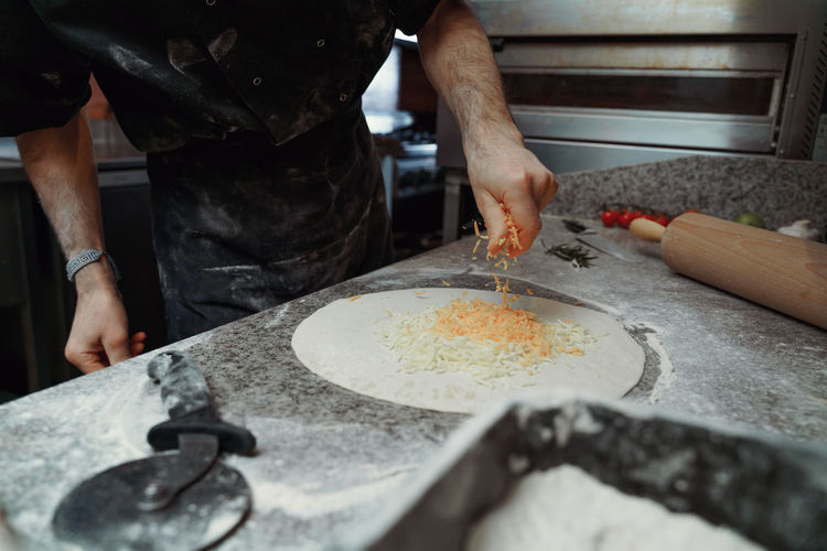 Midsection of man preparing pizza