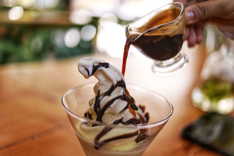 Cropped image of hand pouring caramel on ice cream
