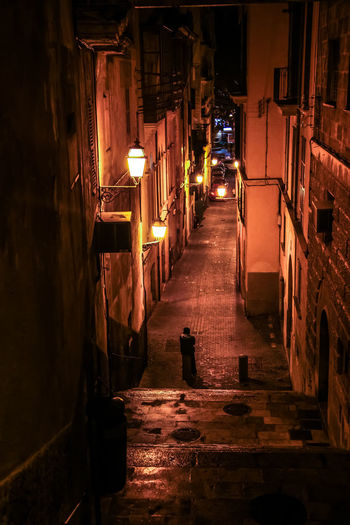 Narrow street amidst buildings in city at night