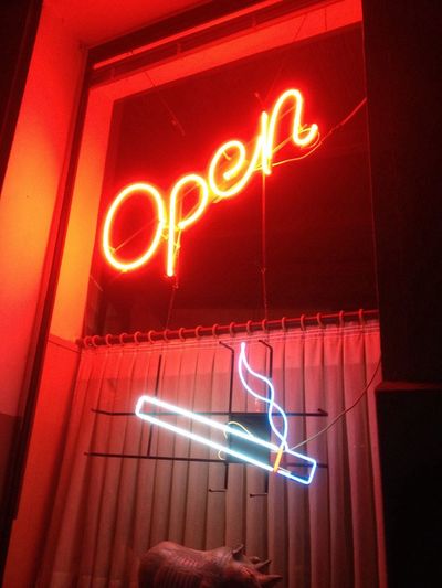 Low angle view of illuminated neon open sign on store window at night