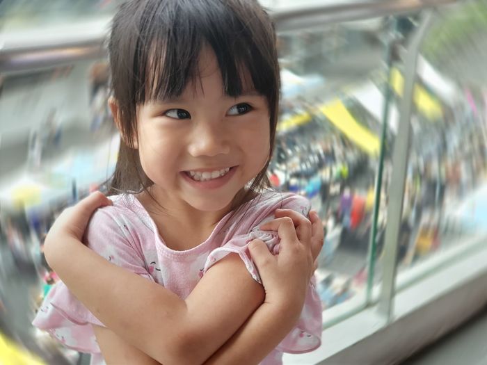 Smiling cute girl looking away while standing by railing