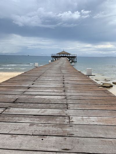 Surface level of wooden pier at sea against sky