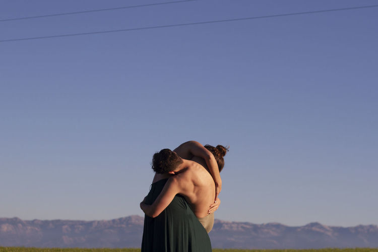 Couple embracing against mountains and clear sky
