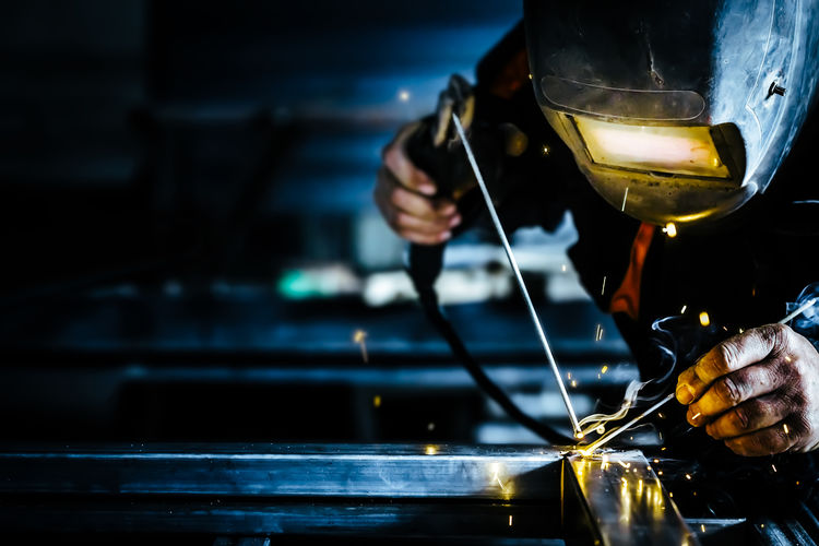 Welder welding metal in factory