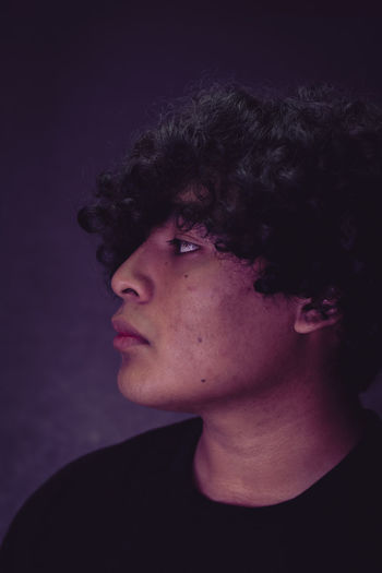 PORTRAIT OF A YOUNG MAN AGAINST BLACK BACKGROUND