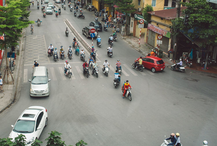 High angle view of people riding motor scooters on road in city