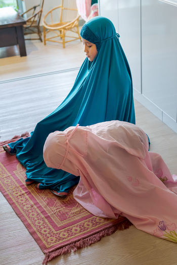 Cute girls in hijab praying at home