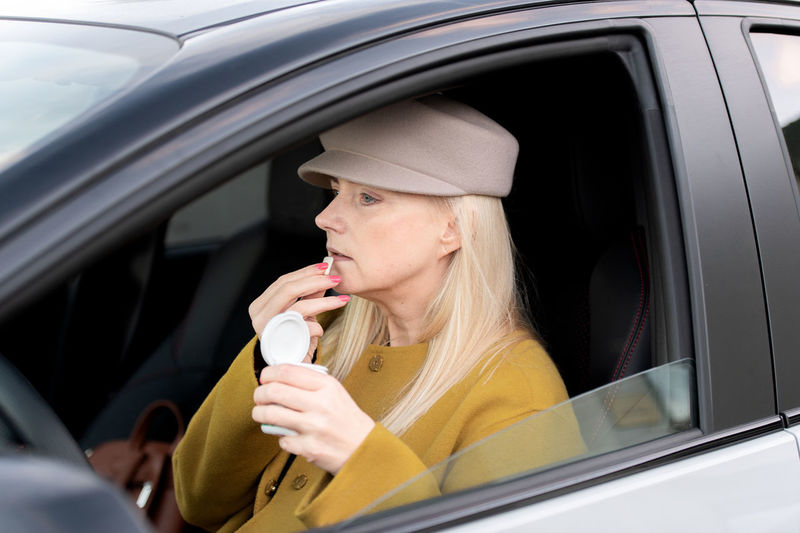 Young woman drinking coffee while sitting in car