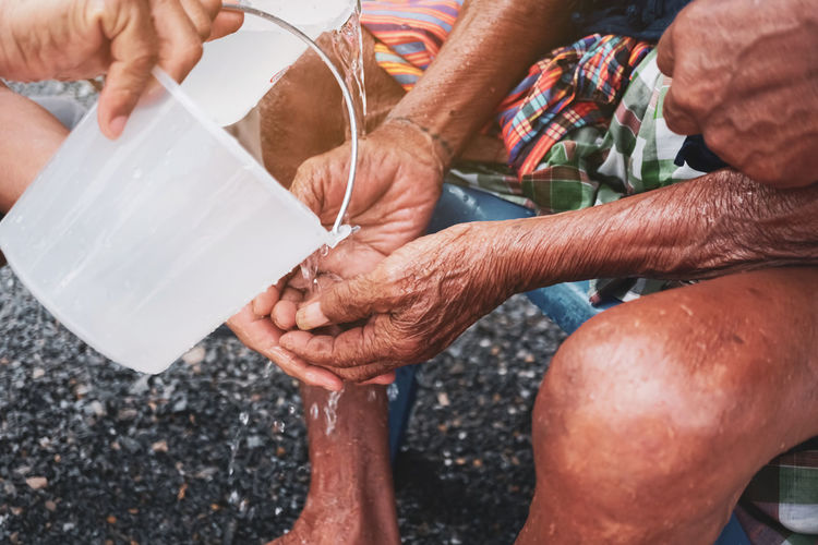 Cropped image of person pouring water on man hands