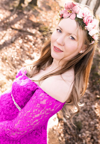 Portrait of beautiful young woman with pink petals on land